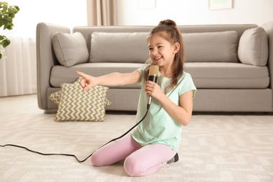 Photo of Cute funny girl with microphone in living room