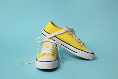 Pair of yellow classic old school sneakers on light blue background