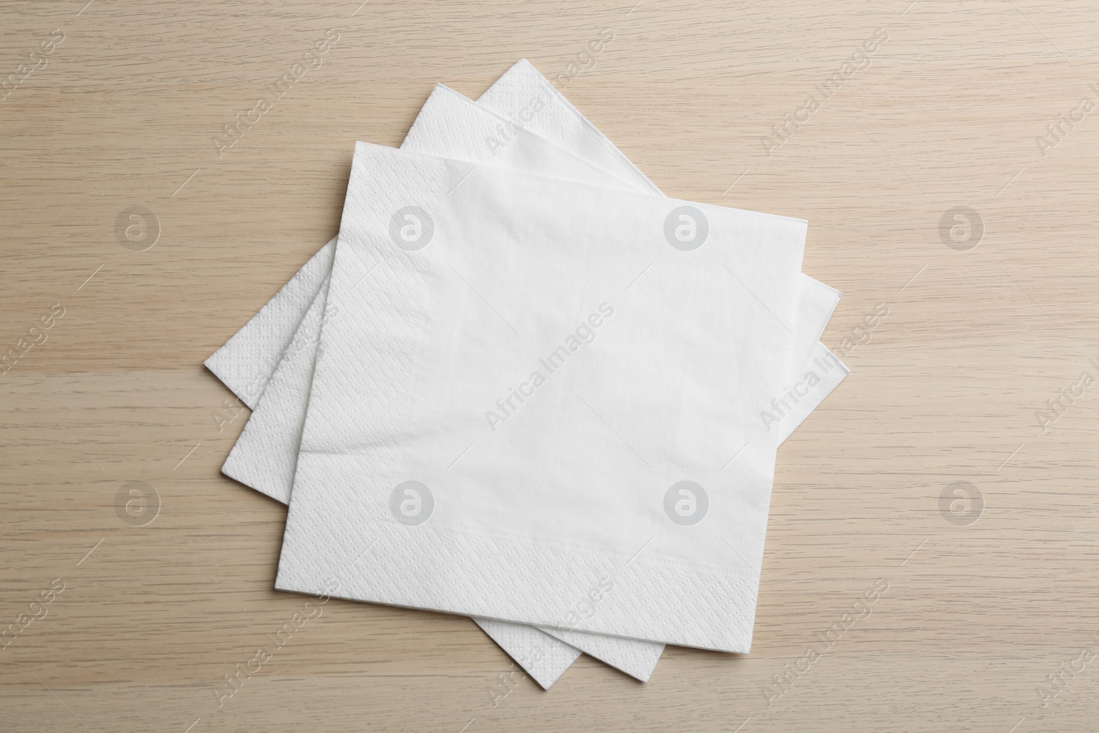 Photo of White clean paper tissues on wooden table, top view