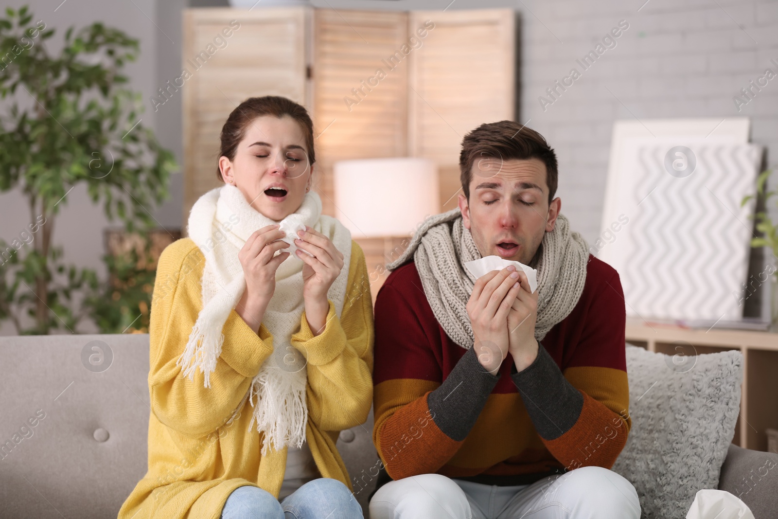 Photo of Couple suffering from cold together on sofa at home