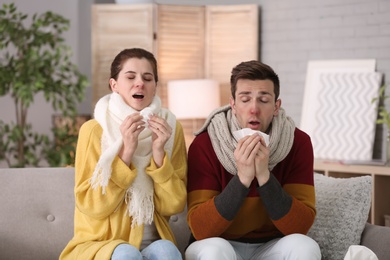 Photo of Couple suffering from cold together on sofa at home