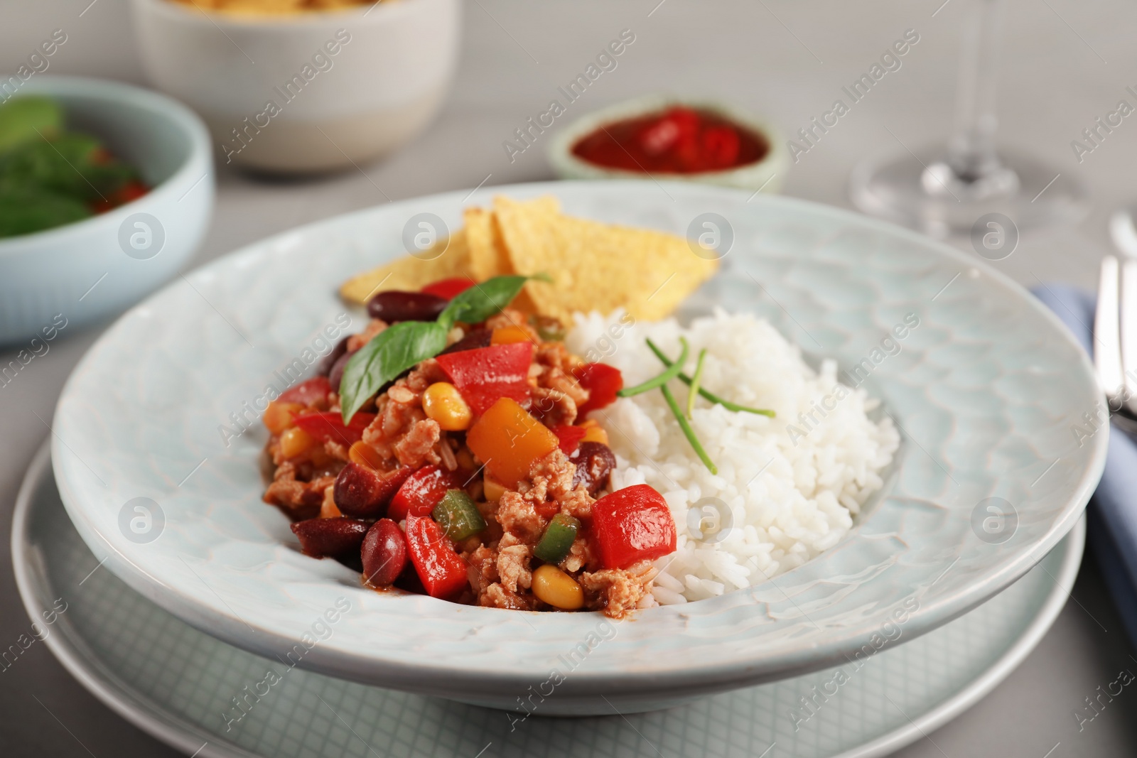 Photo of Tasty chili con carne served with rice on gray table