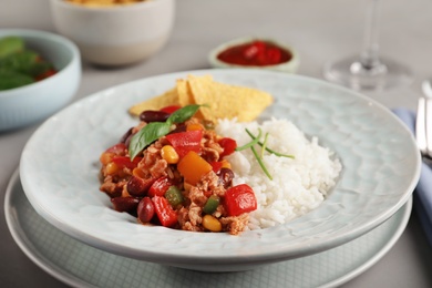 Tasty chili con carne served with rice on gray table