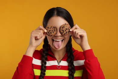 Photo of Young woman with chocolate chip cookies on orange background