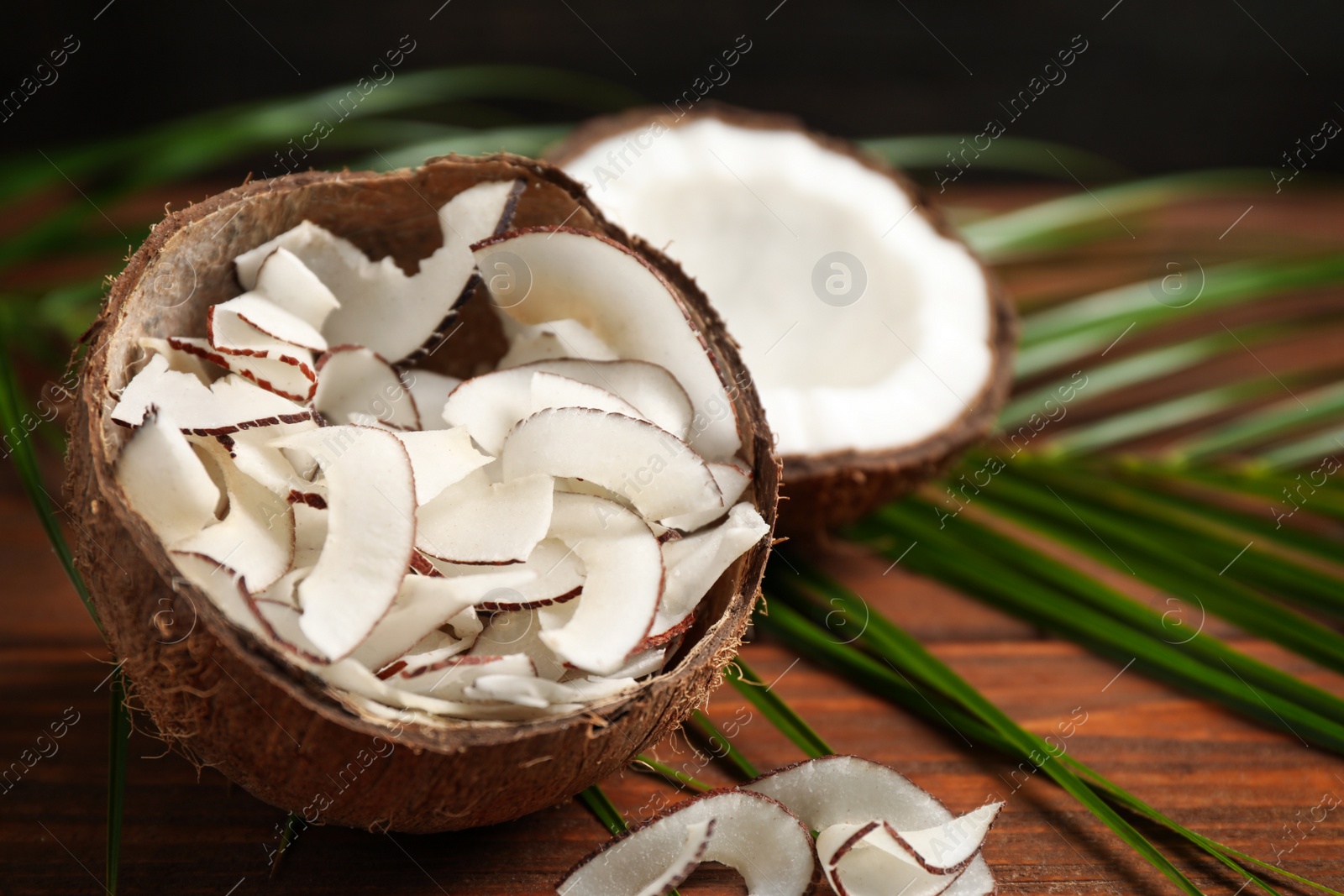 Photo of Tasty coconut chips on wooden table, closeup. Space for text