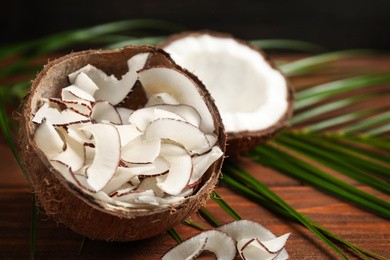 Tasty coconut chips on wooden table, closeup. Space for text