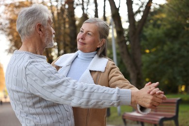 Photo of Affectionate senior couple dancing together in park. Romantic date