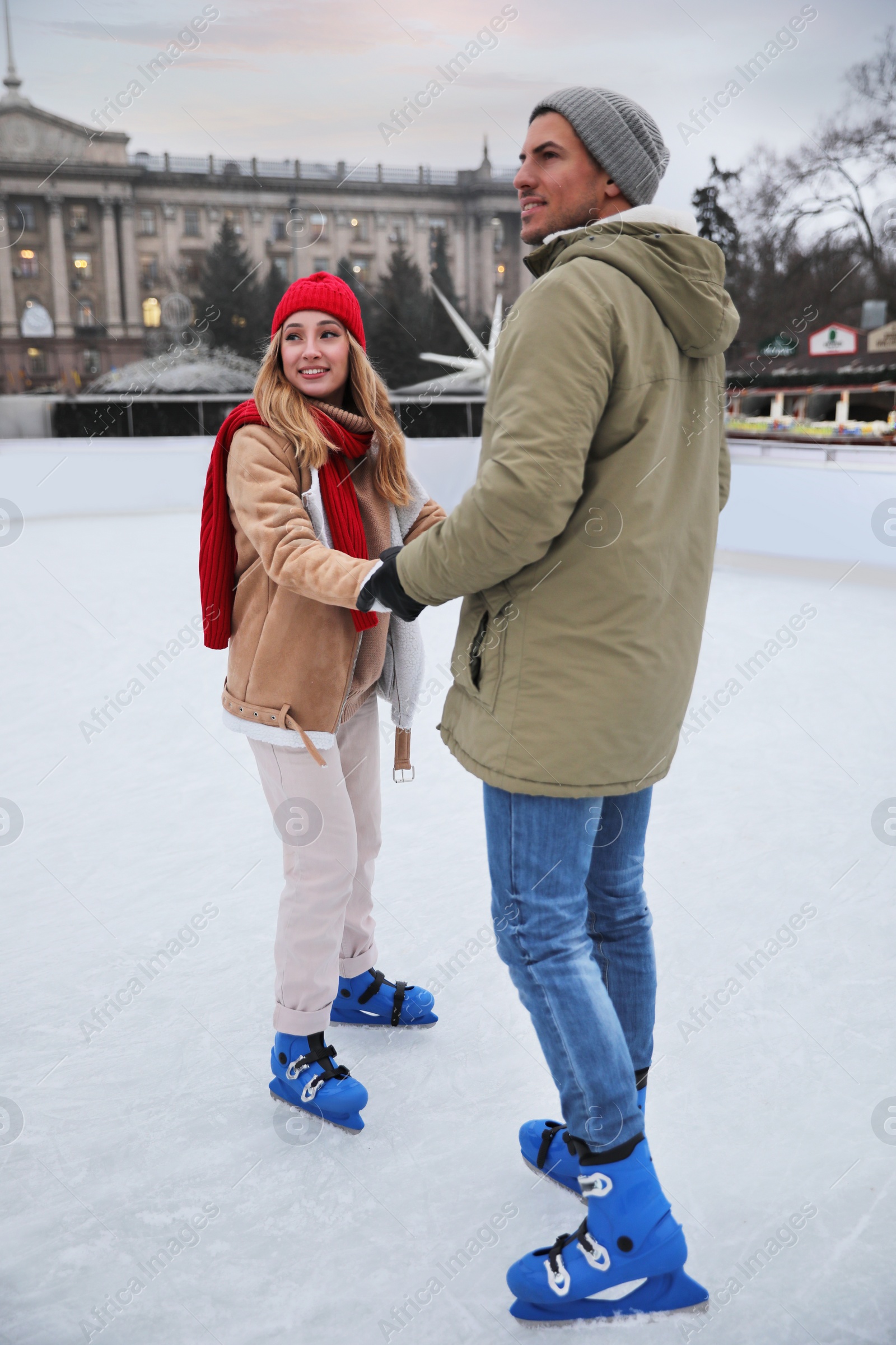 Image of Happy couple skating at outdoor ice rink