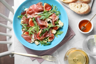 Photo of Salad with ripe figs and prosciutto served on grey marble table indoors, top view