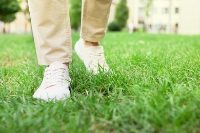 Photo of Man in stylish sneakers walking on green grass outdoors, closeup