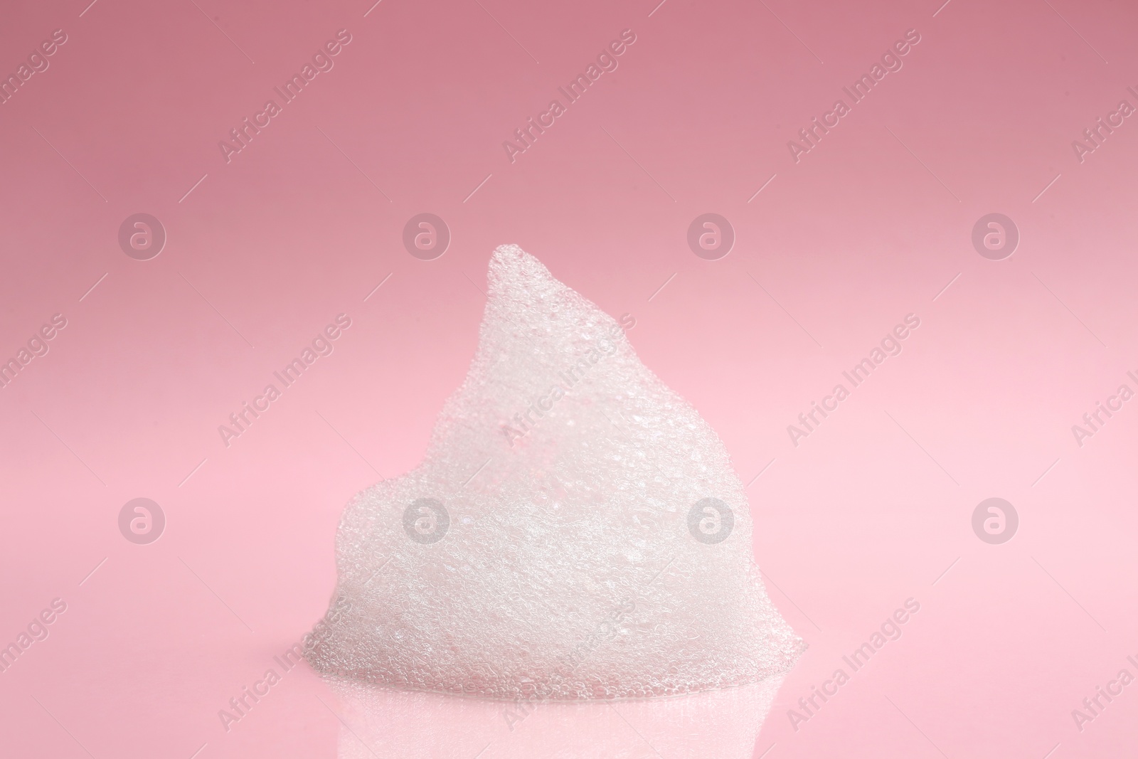 Photo of Drop of fluffy bath foam on pink background