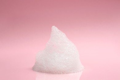 Photo of Drop of fluffy bath foam on pink background