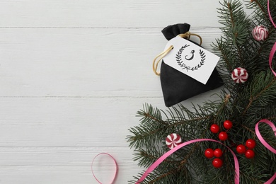 Photo of Bag with gift, festive decor and space for text on white wooden table, flat lay. Christmas advent calendar