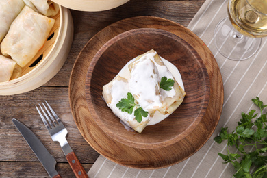 Photo of Delicious cabbage rolls served on wooden table, flat lay