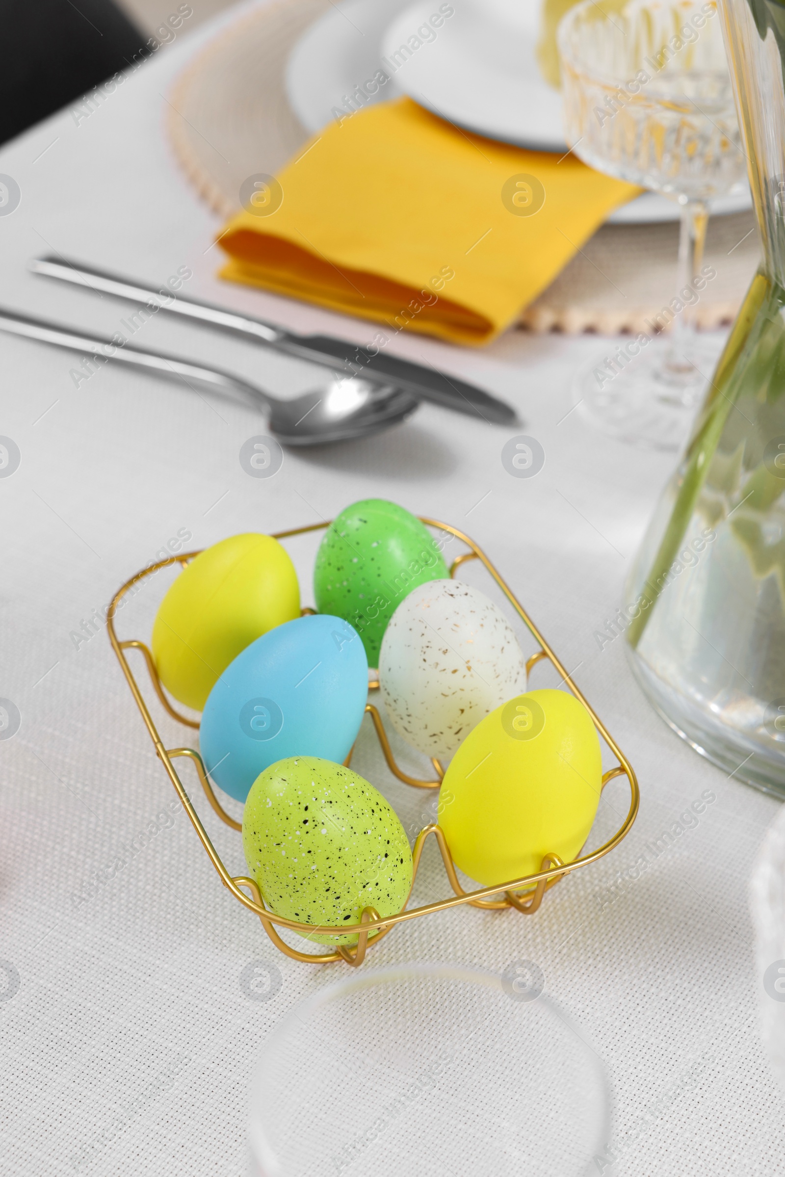 Photo of Festive table setting with painted eggs and cutlery. Easter celebration