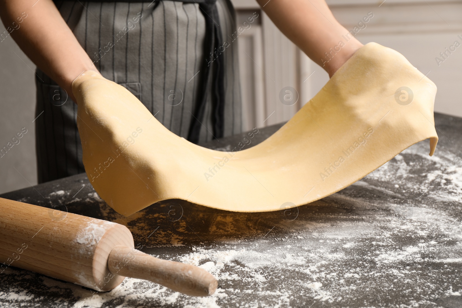 Photo of Woman with dough at grey table, closeup. Making pasta