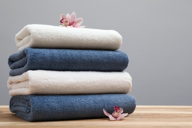 Photo of Stack of fresh towels with flowers on table. Space for text