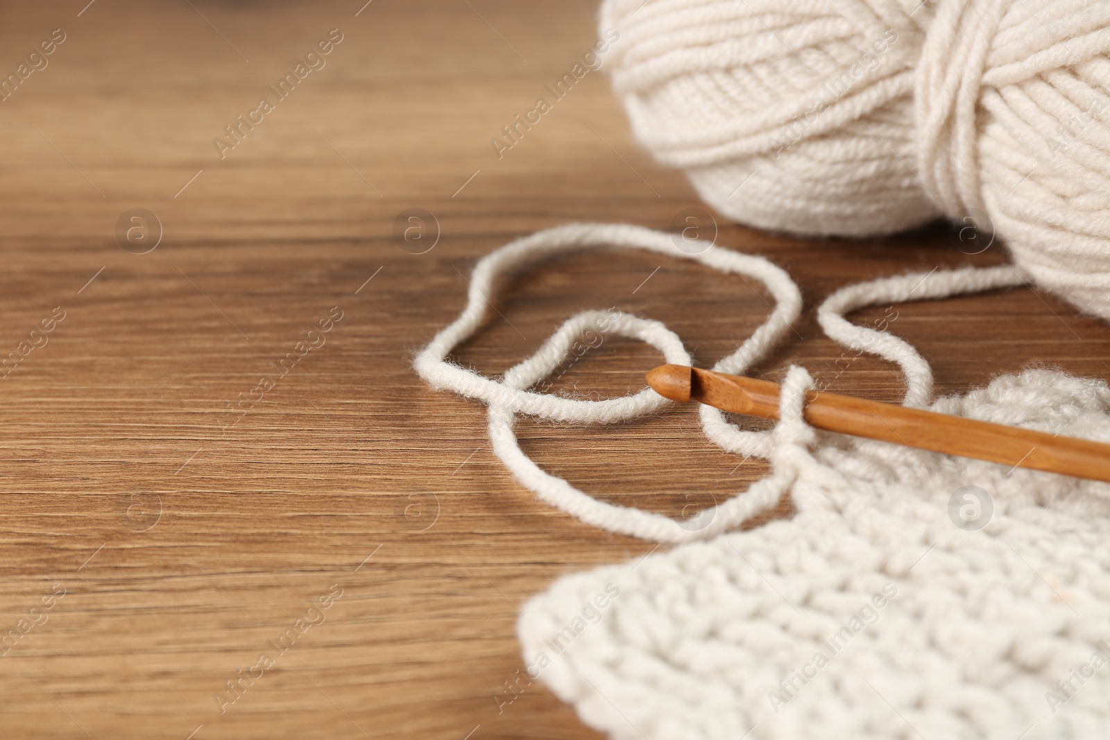 Photo of Knitting and crochet hook on wooden table, closeup. Space for text