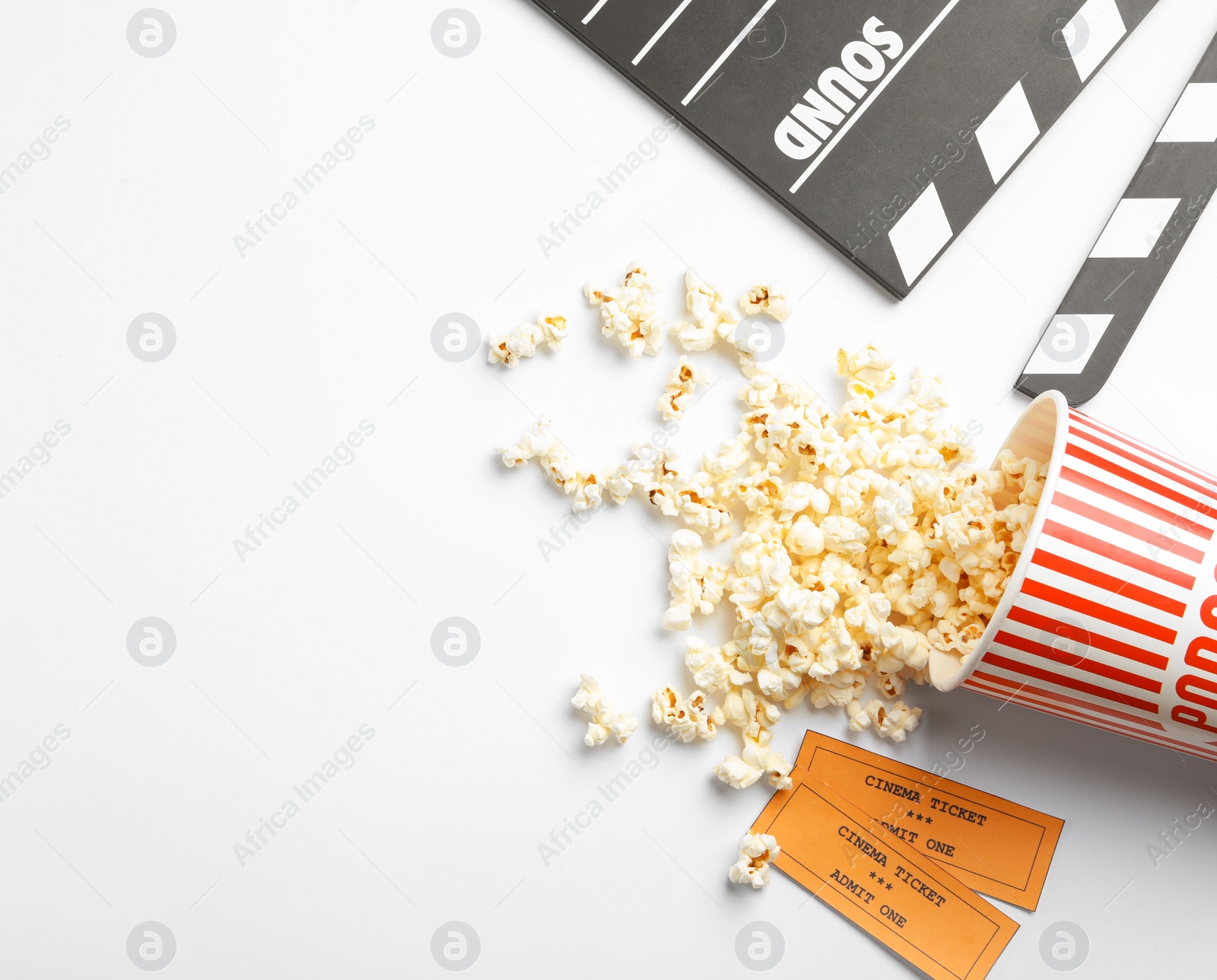 Photo of Clapperboard, popcorn and tickets on white background, top view. Cinema snack