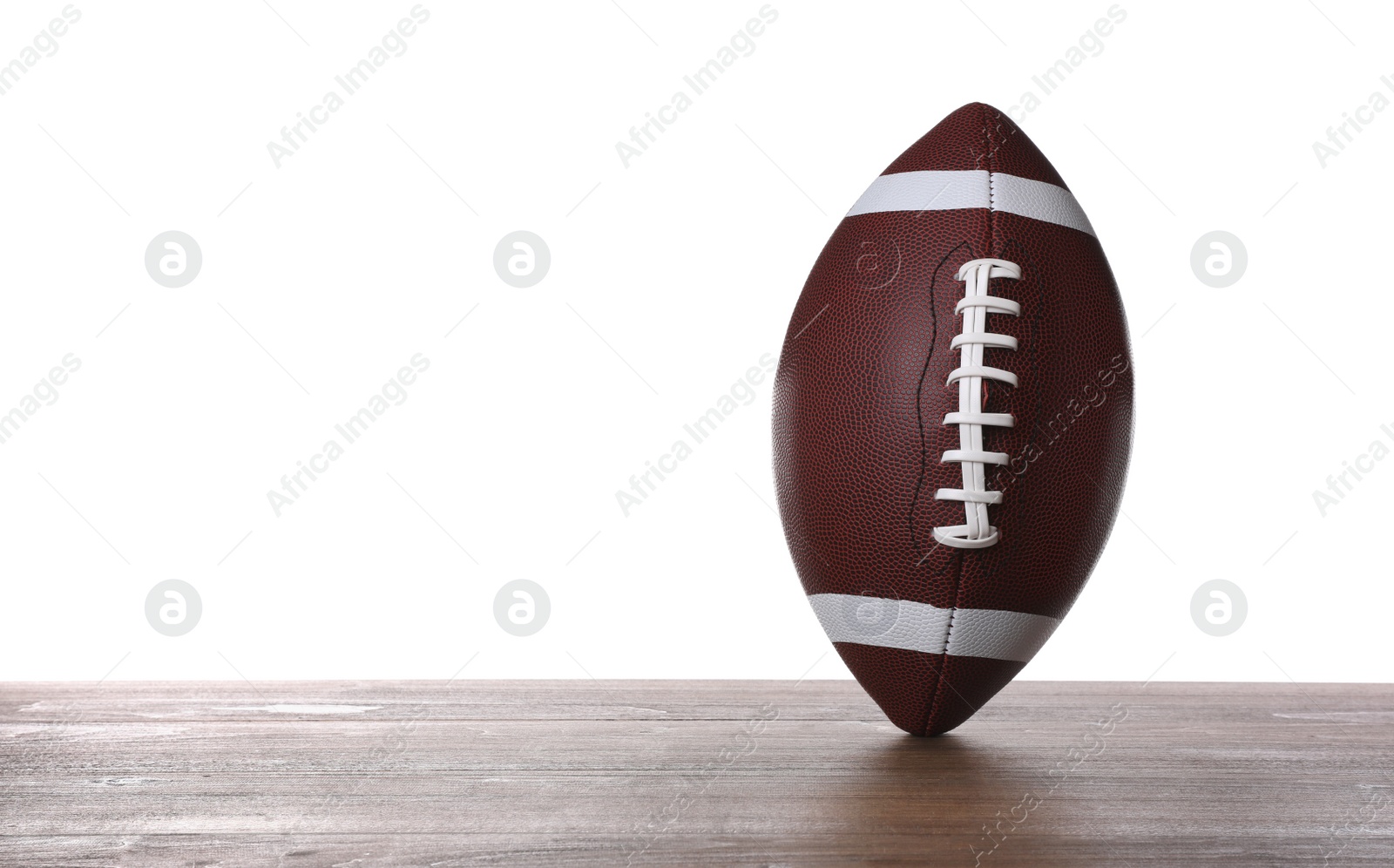 Photo of American football ball on wooden table against white background. Space for text