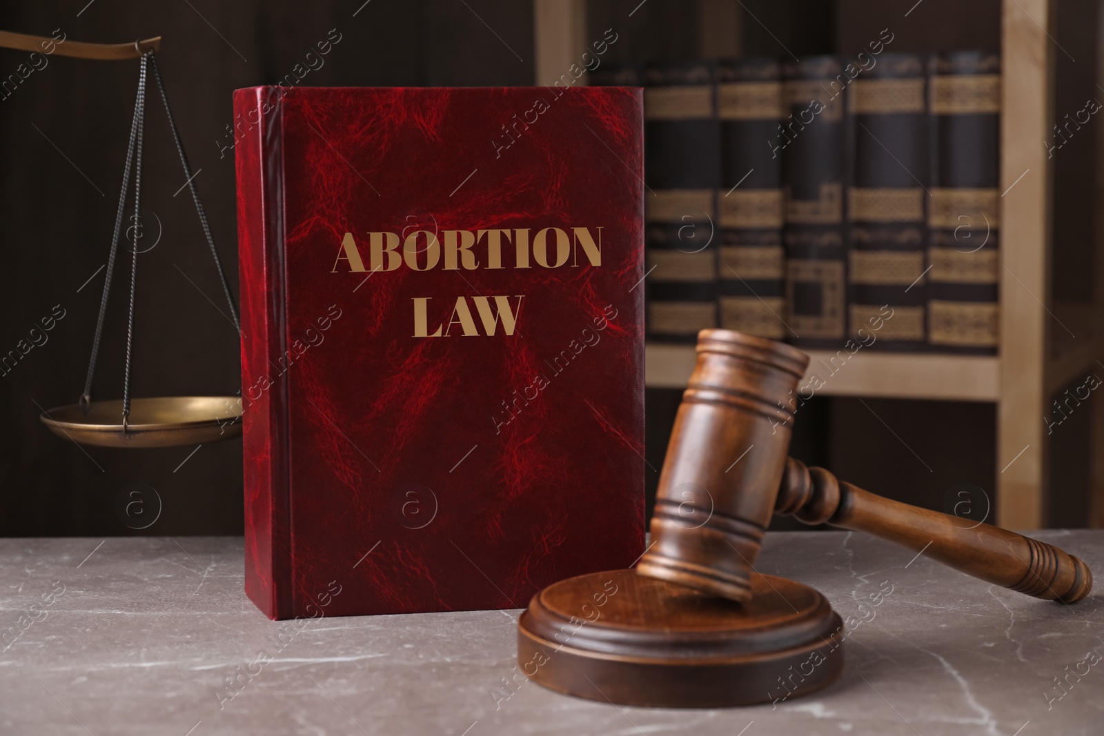 Image of Abortion Law book, gavel and scales of justice on brown marble table