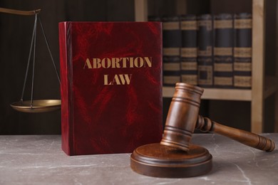 Abortion Law book, gavel and scales of justice on brown marble table