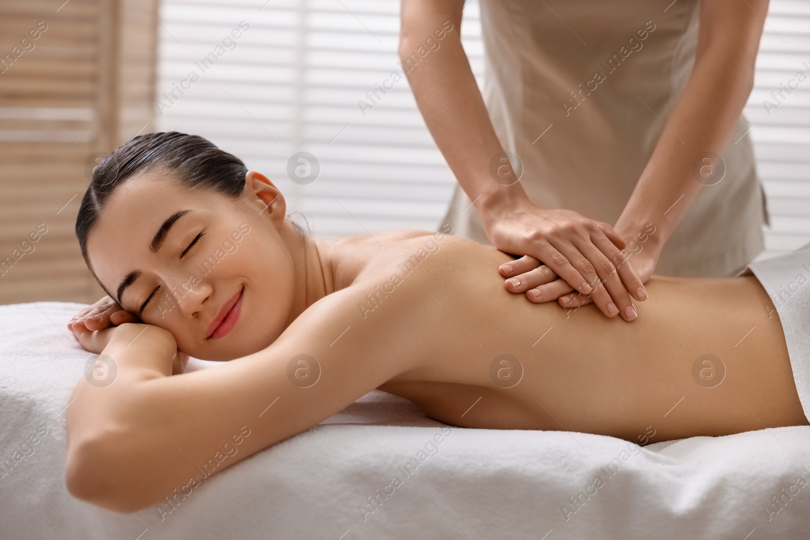 Photo of Woman receiving back massage on couch in spa salon