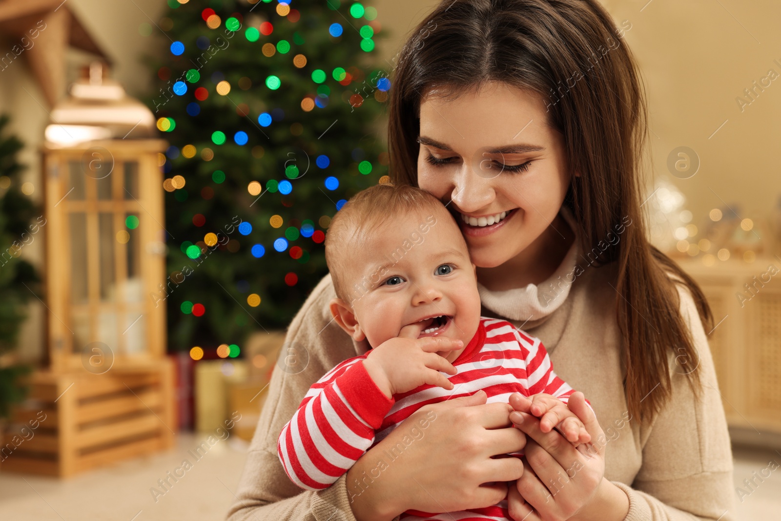 Photo of Happy young mother with her cute baby in room decorated for Christmas. Winter holiday