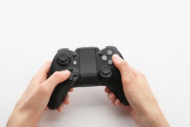 Photo of Young woman holding video game controller on white background, closeup