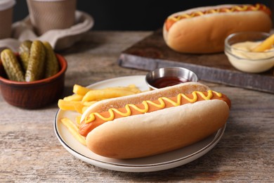 Delicious hot dog with ketchup, mustard and French fries on wooden table, closeup