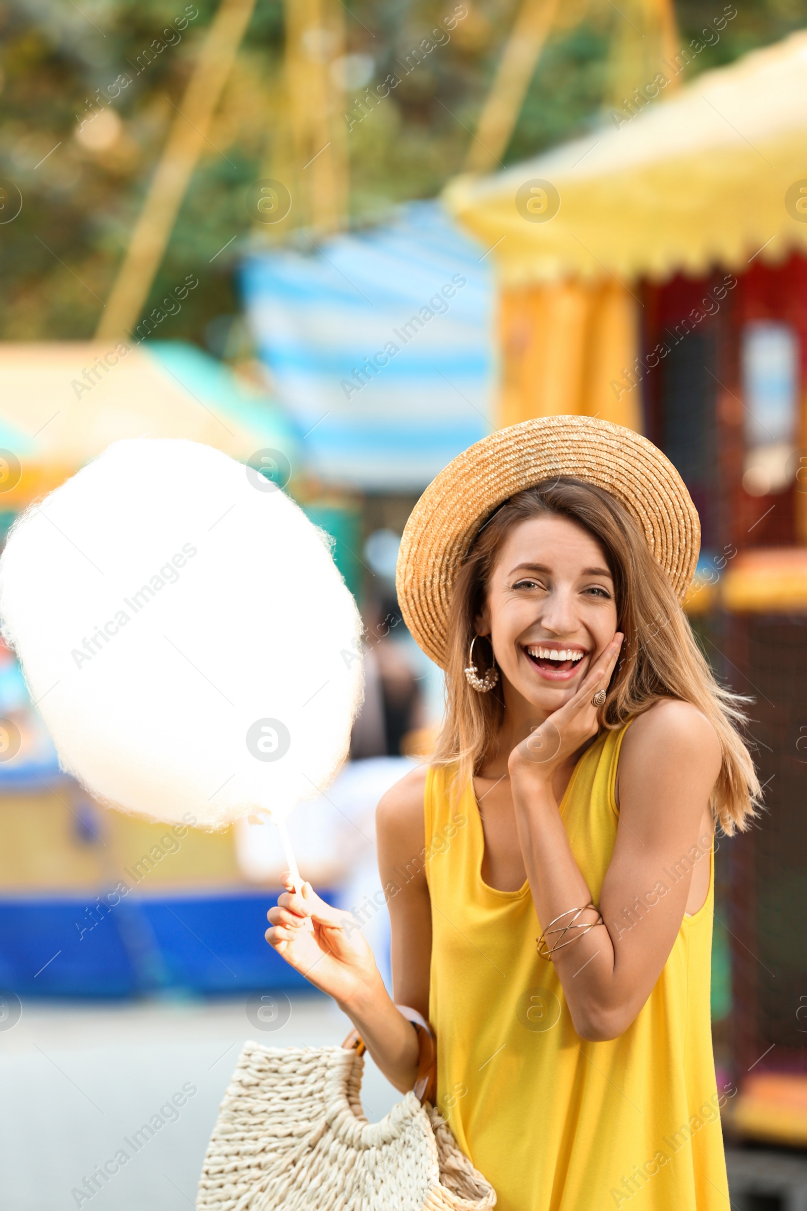 Photo of Happy young woman with cotton candy in amusement park