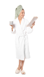 Beautiful young woman in bathrobe reading newspaper on white background