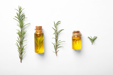 Bottles of rosemary oil and fresh twigs on white background, top view