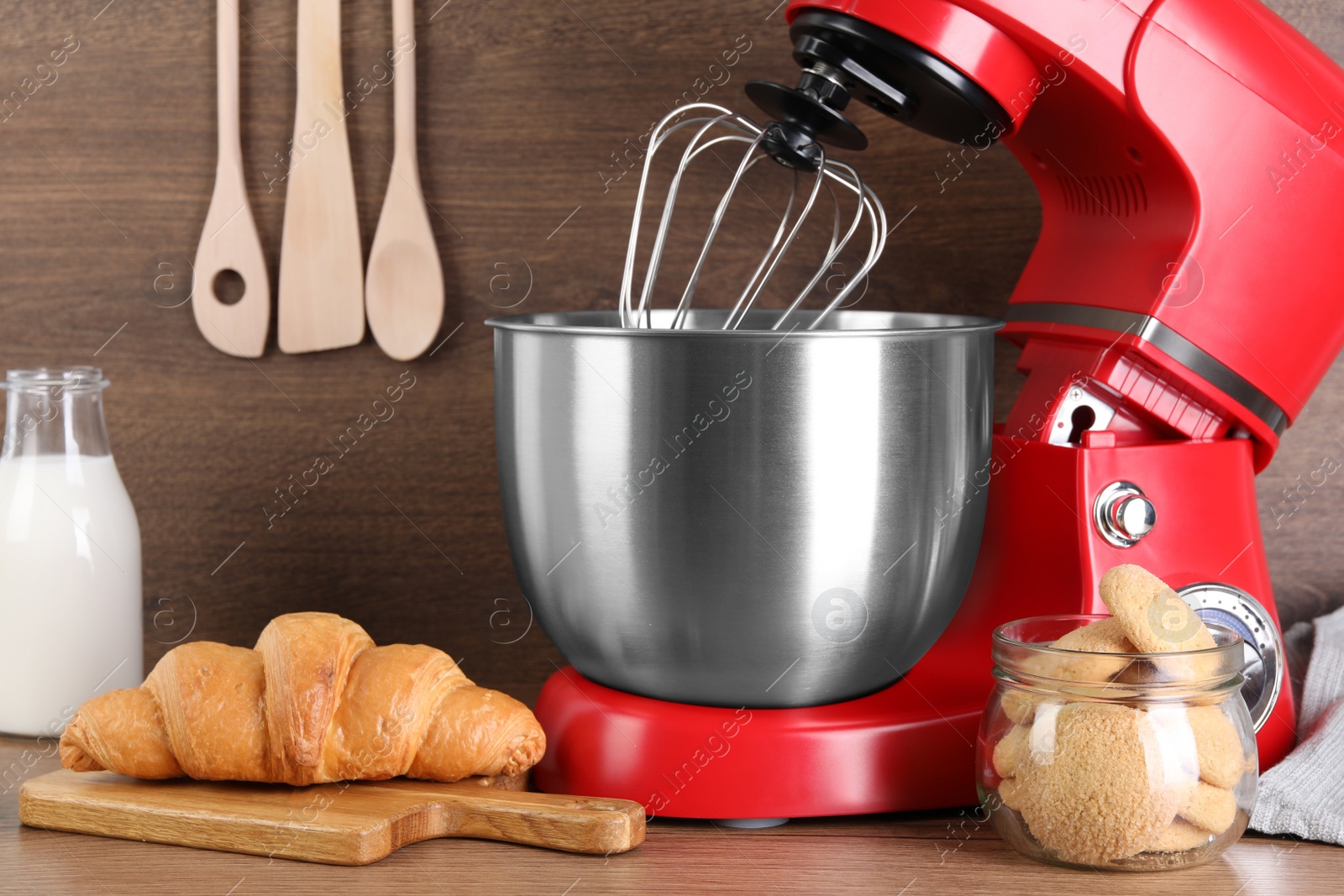 Photo of Modern red stand mixer, croissant and cookies on wooden table