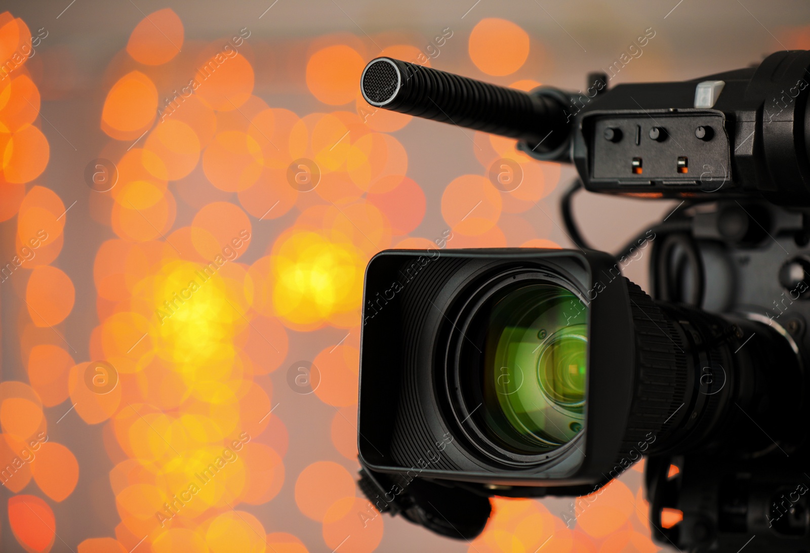 Photo of Modern video camera against blurred lights, closeup