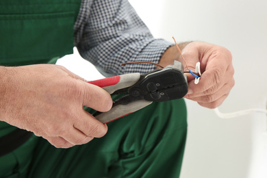 Image of Professional electrician stripping wire ends indoors, closeup