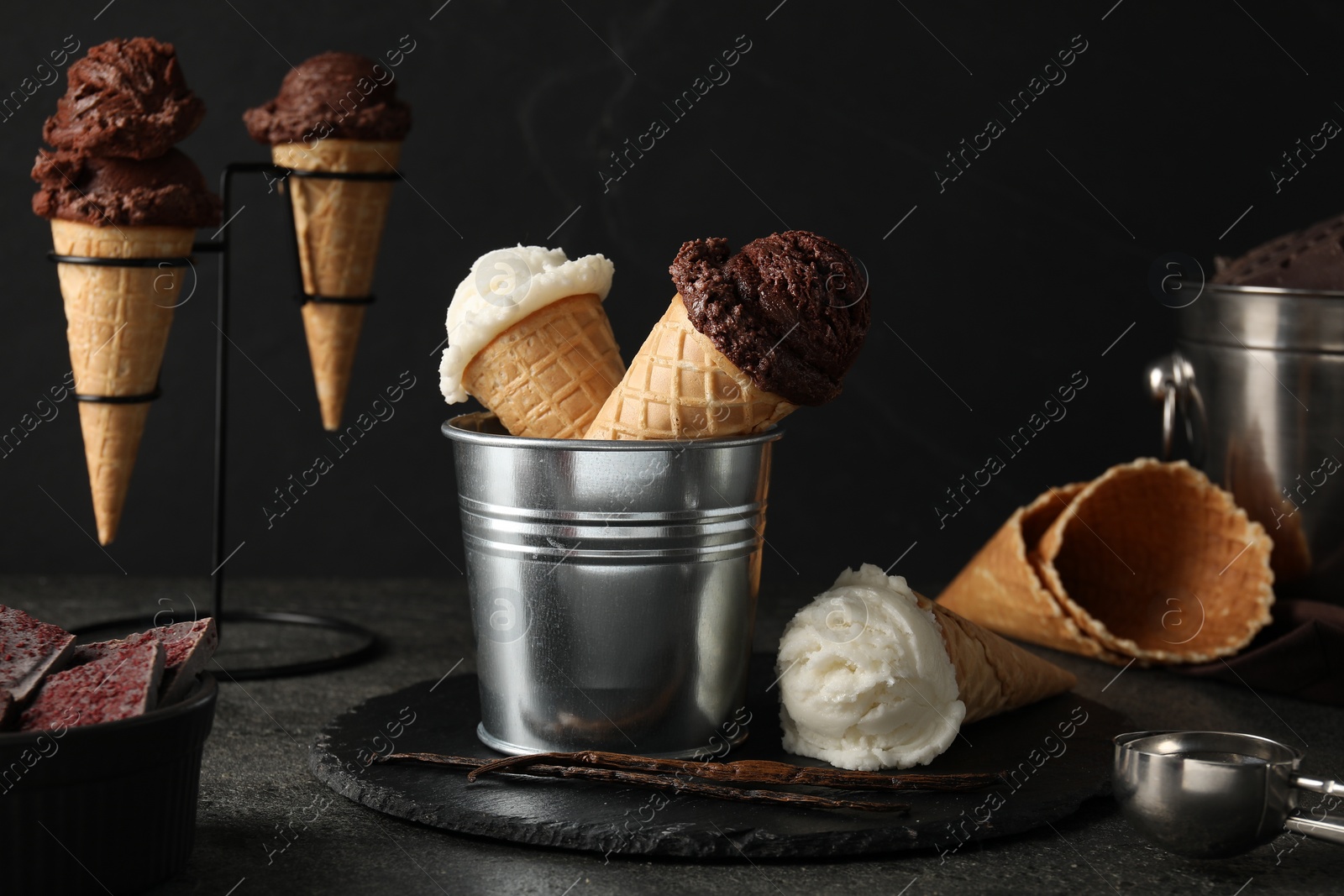 Photo of Ice cream scoops in wafer cones on gray textured table