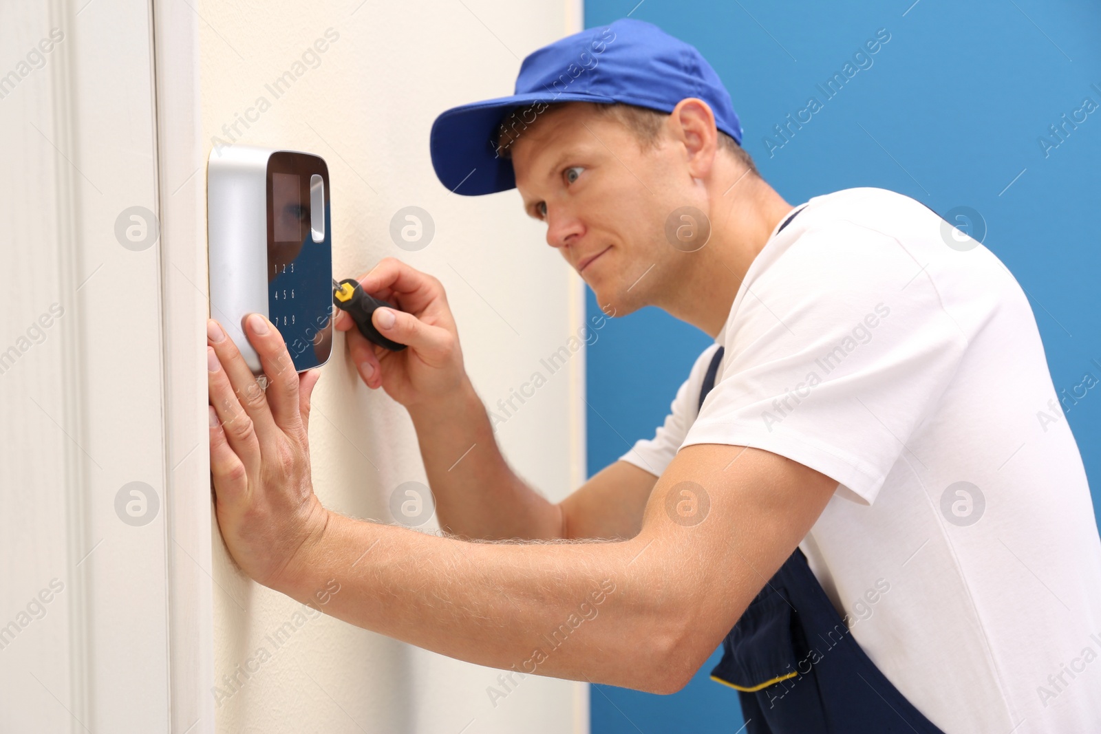 Photo of Male technician installing security alarm system indoors