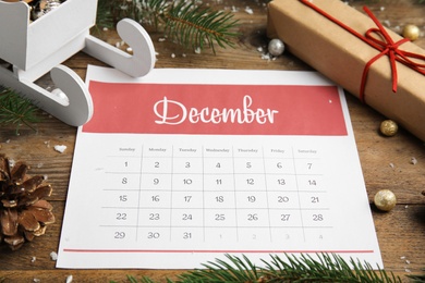 Photo of Paper calendar and festive decor on wooden table