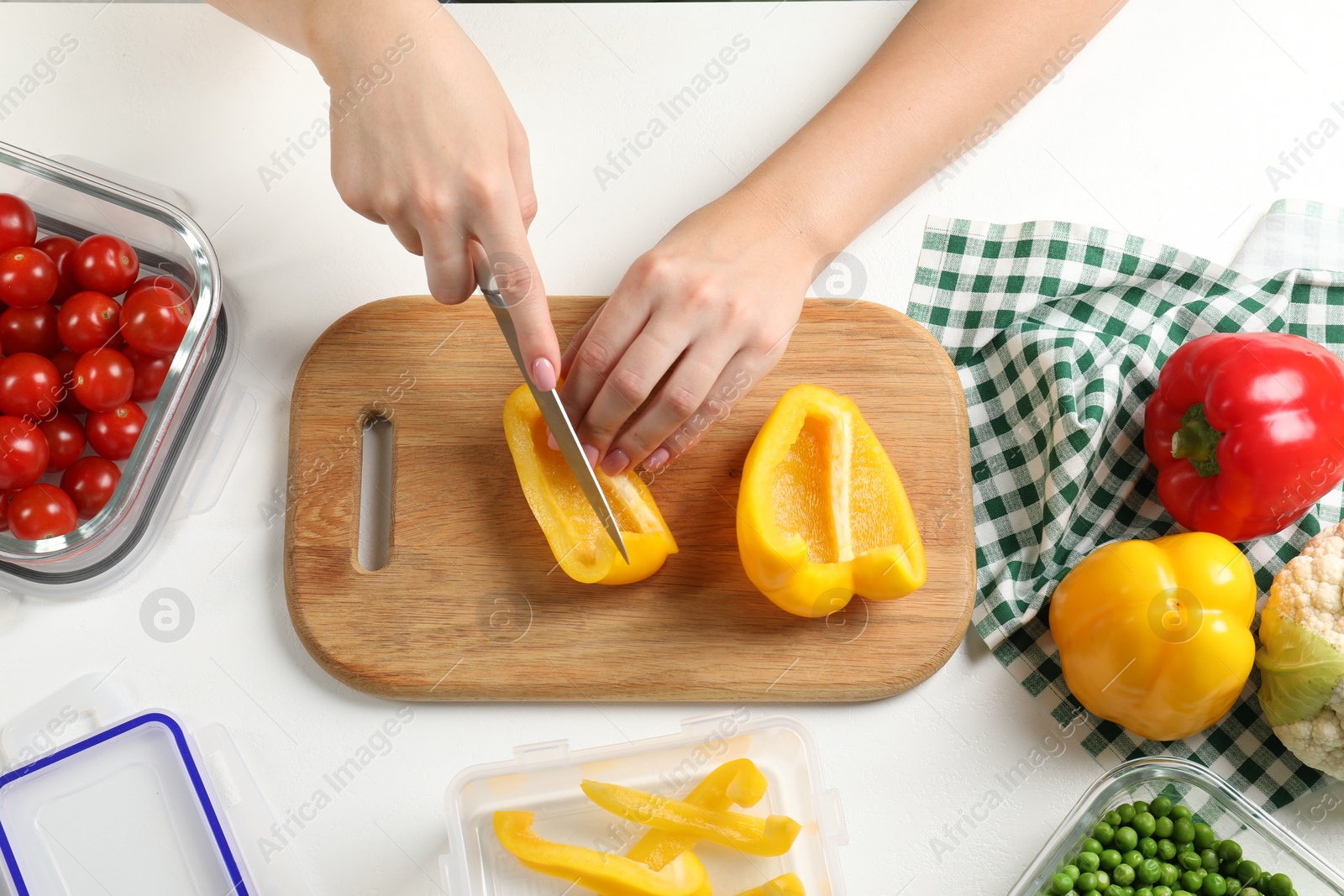 Photo of Woman cutting bell pepper and containers with fresh products on white table, flat lay. Food storage