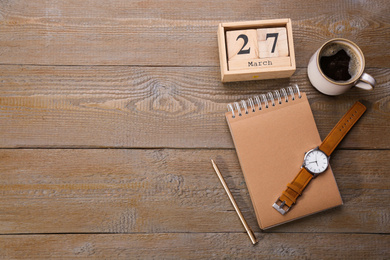 Photo of Flat lay composition with calendar and cup of coffee on wooden table. Space for text