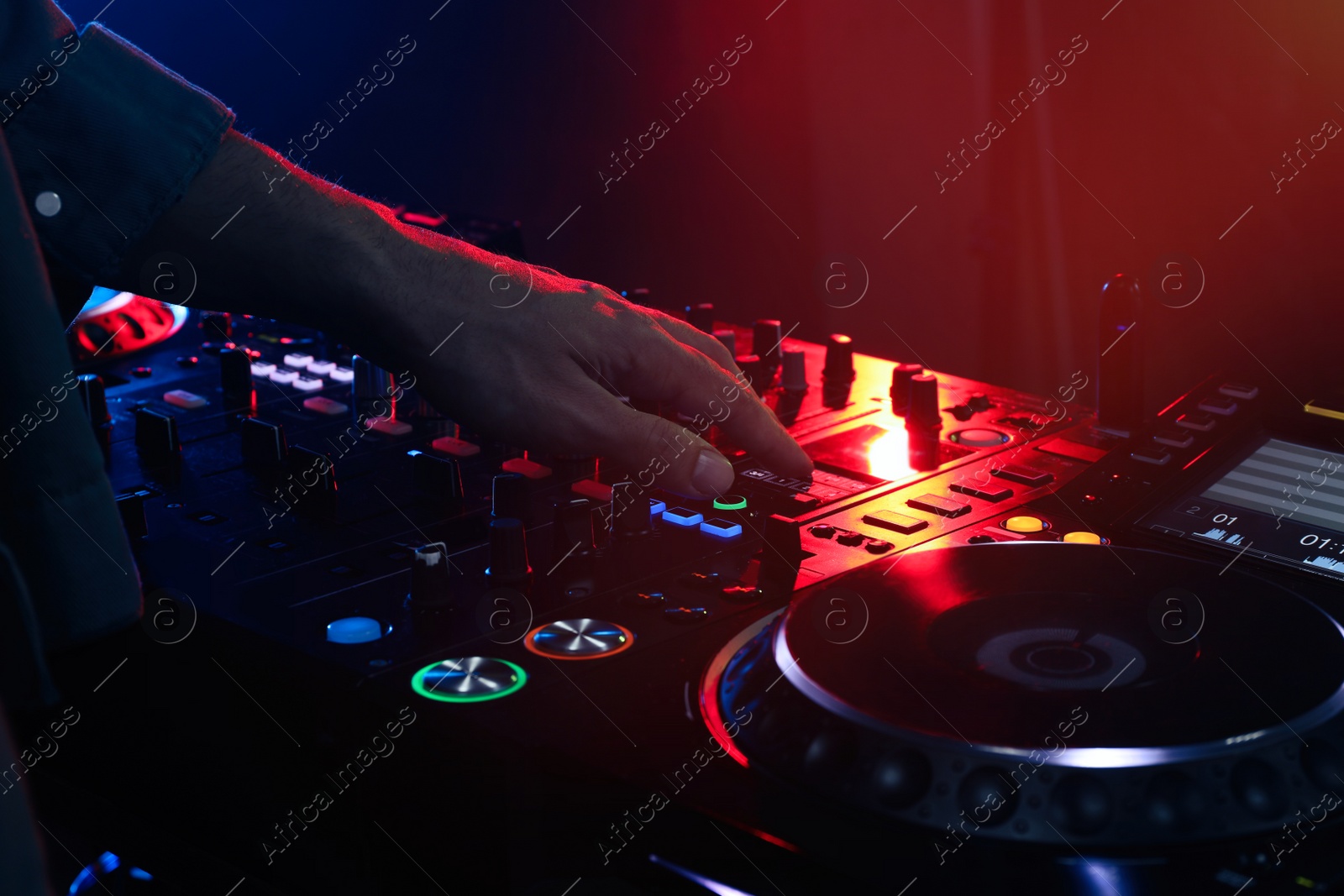 Photo of DJ creating music on modern console mixer in night club, closeup