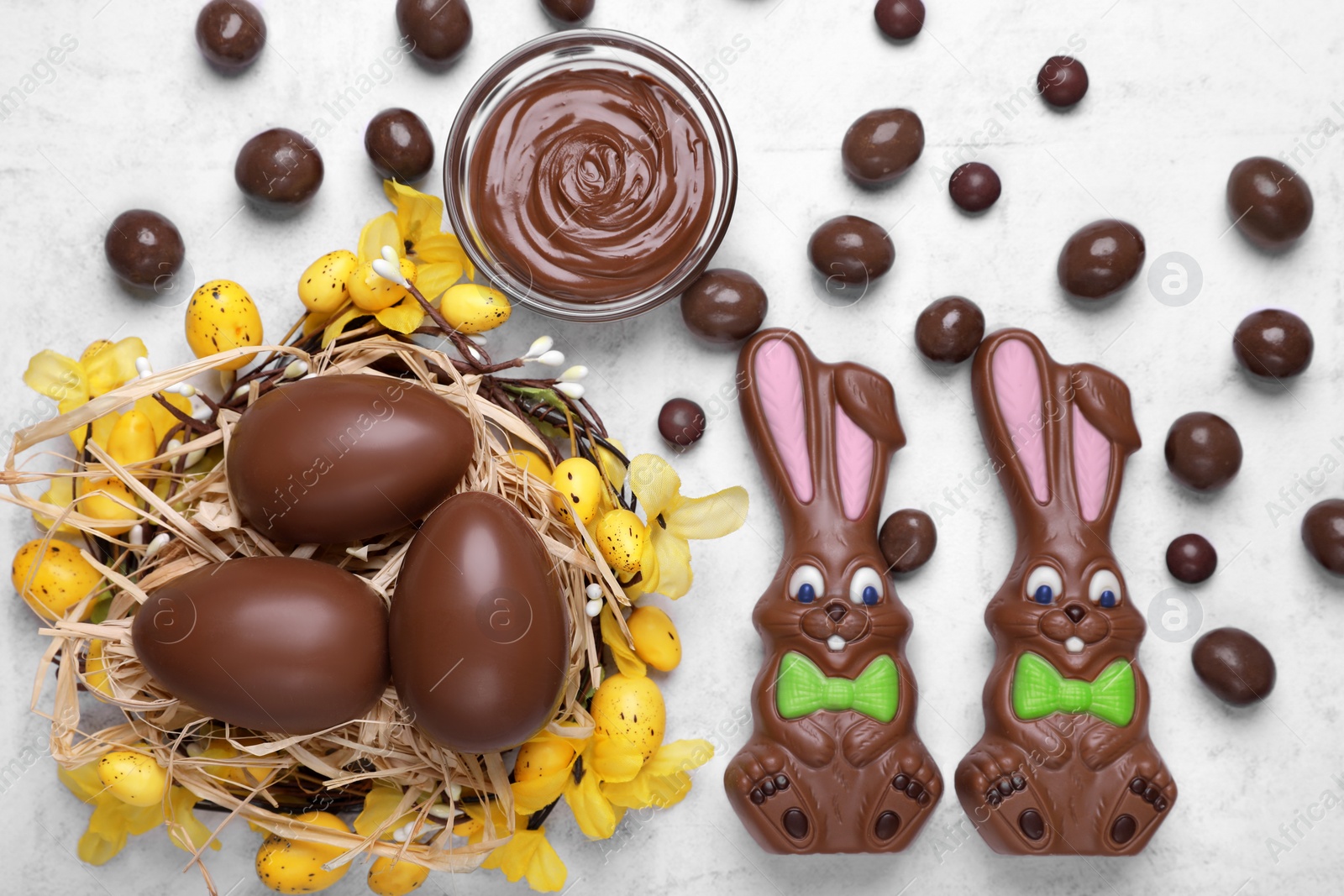 Photo of Flat lay composition with chocolate Easter bunnies, eggs and candies on white textured table