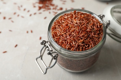 Photo of Brown rice in glass jar on table. Space for text