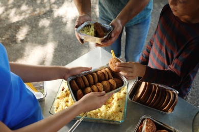 Photo of Volunteer serving food to poor people outdoors, closeup