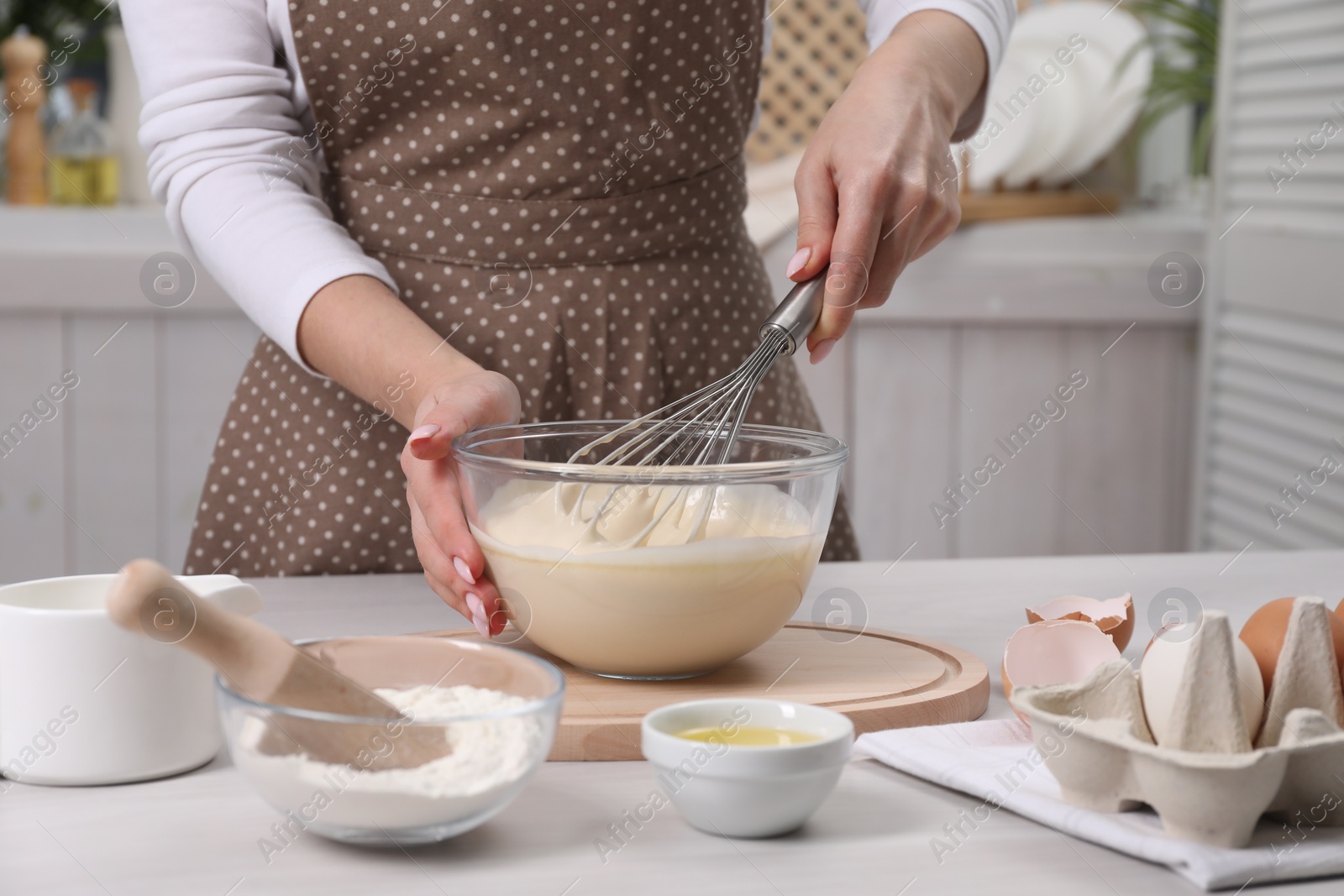 Photo of Woman making dough with whisk in bowl at table, closeup