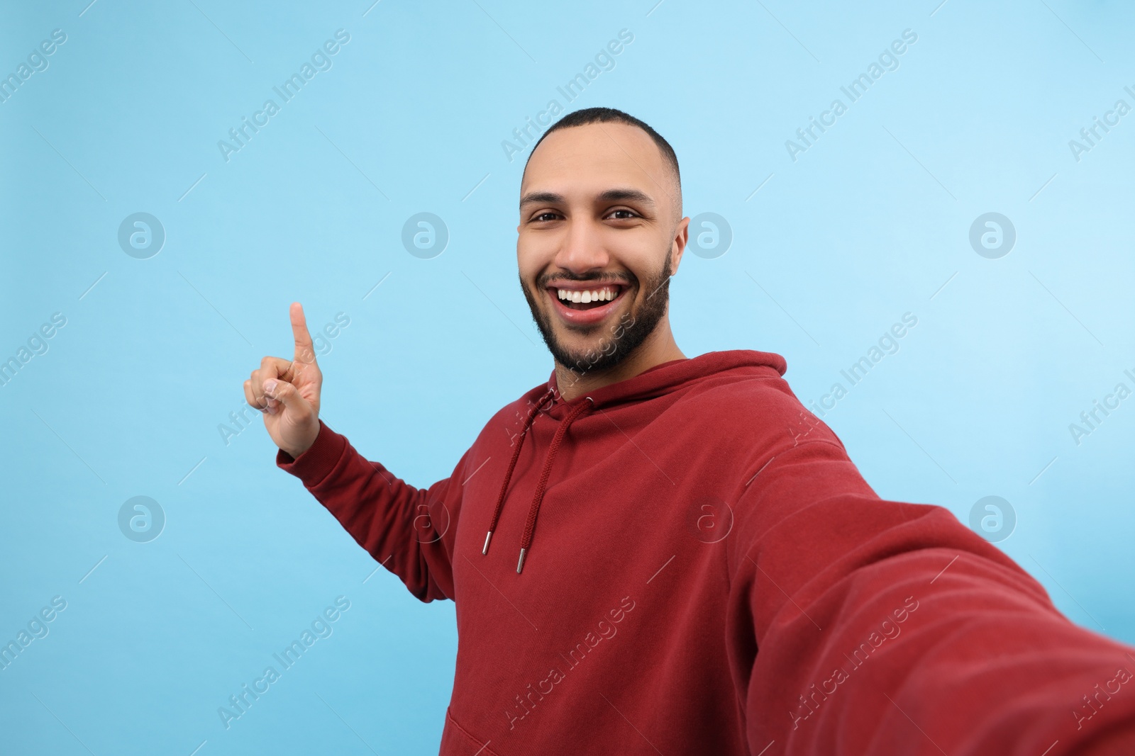 Photo of Smiling young man taking selfie on light blue background