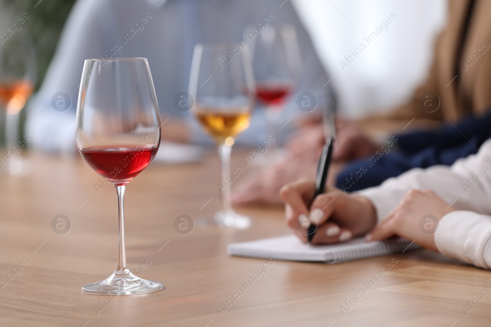 Photo of Sommeliers making notes during wine tasting at table indoors, closeup