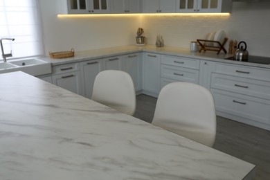 Photo of Modern kitchen interior with white marble table and stylish chairs