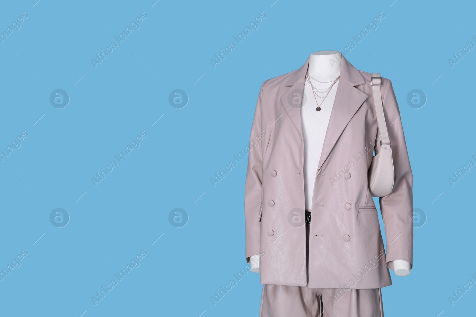 Photo of Female mannequin dressed in white t-shirt and stylish leather suit with accessories on light blue background, space for text